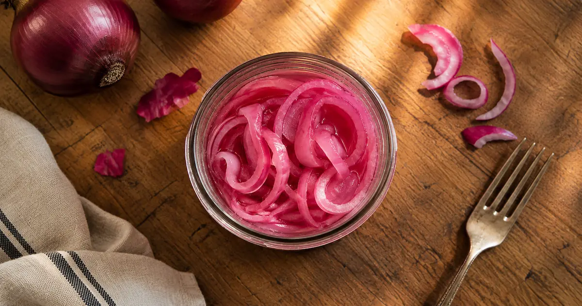 pint jar of pickled red onions on wooden counter