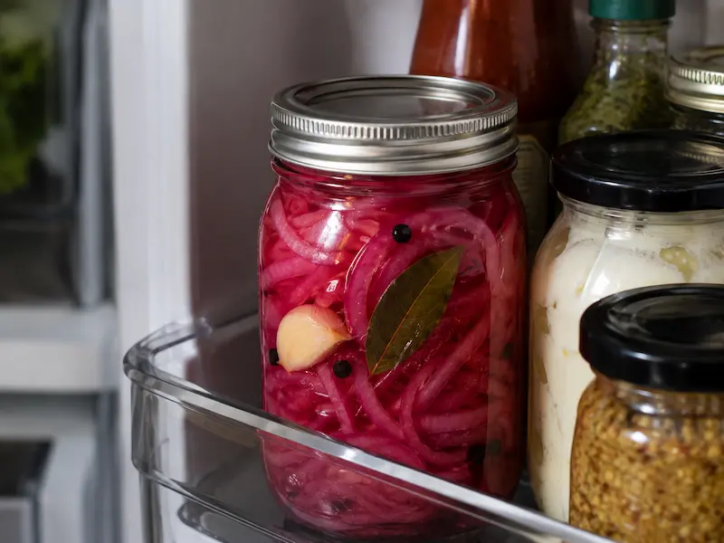 traditional pickled red onions with garlic and bay leaf in fridge